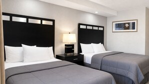 A hotel room with two beds, a nightstand with a lamp, and a framed picture on the wall.