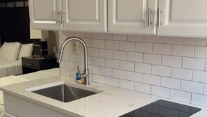 A modern kitchen with white cabinetry, a double sink, and a black stovetop.