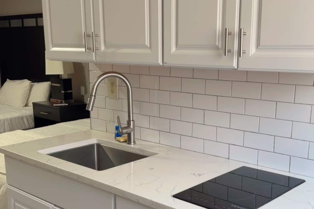 A modern kitchen with white cabinetry, a double sink, and a black stovetop.