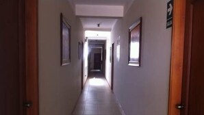 Un pasillo largo y estrecho con puertas a ambos lados, que conduce a una habitación luminosa al final.