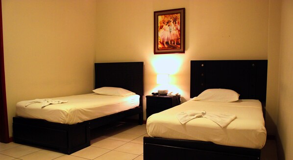 Two single beds with headboards, a nightstand with a lamp, and a framed picture on the wall.