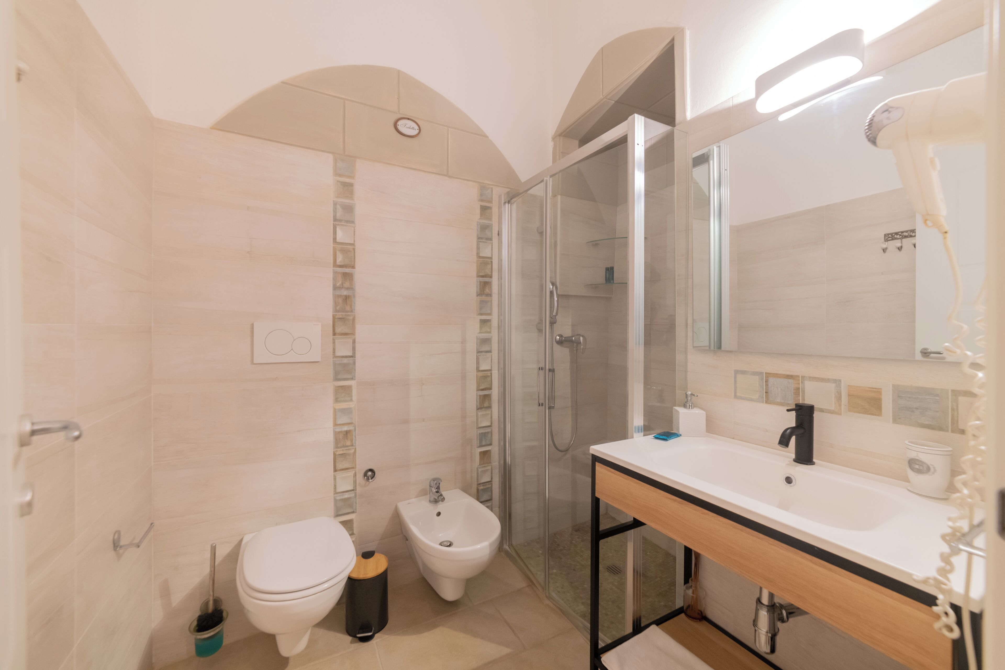Un baño moderno con ducha, bidé, inodoro y tocador con espejo y lavamanos.