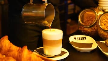 A person pouring a beverage into a cup, a croissant, and a plate with '4 latas' text.