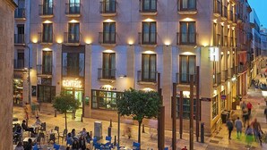 Un hotel con terraza, un bar cafetería y una entrada principal.