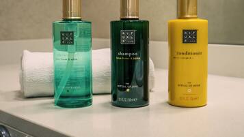 Três frascos de produtos Ritual of Mehr sobre uma bancada de banheiro.