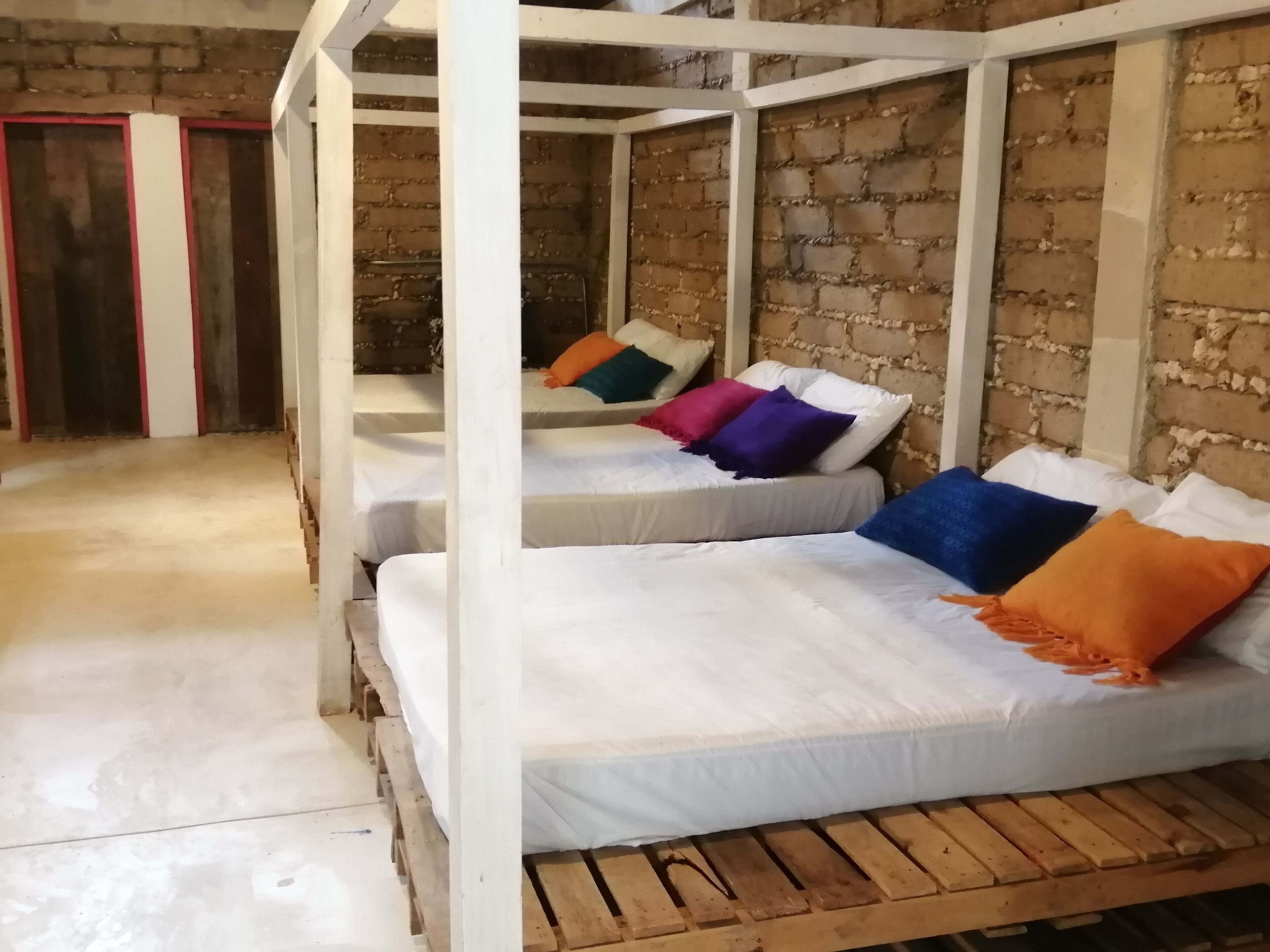Una habitación con tres literas de madera, cada una con ropa de cama blanca y almohadas de colores.