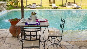 A poolside table with chairs, a vase with flowers, and a dining setup. - Canto del Agua Ecolodge (Tzimol)