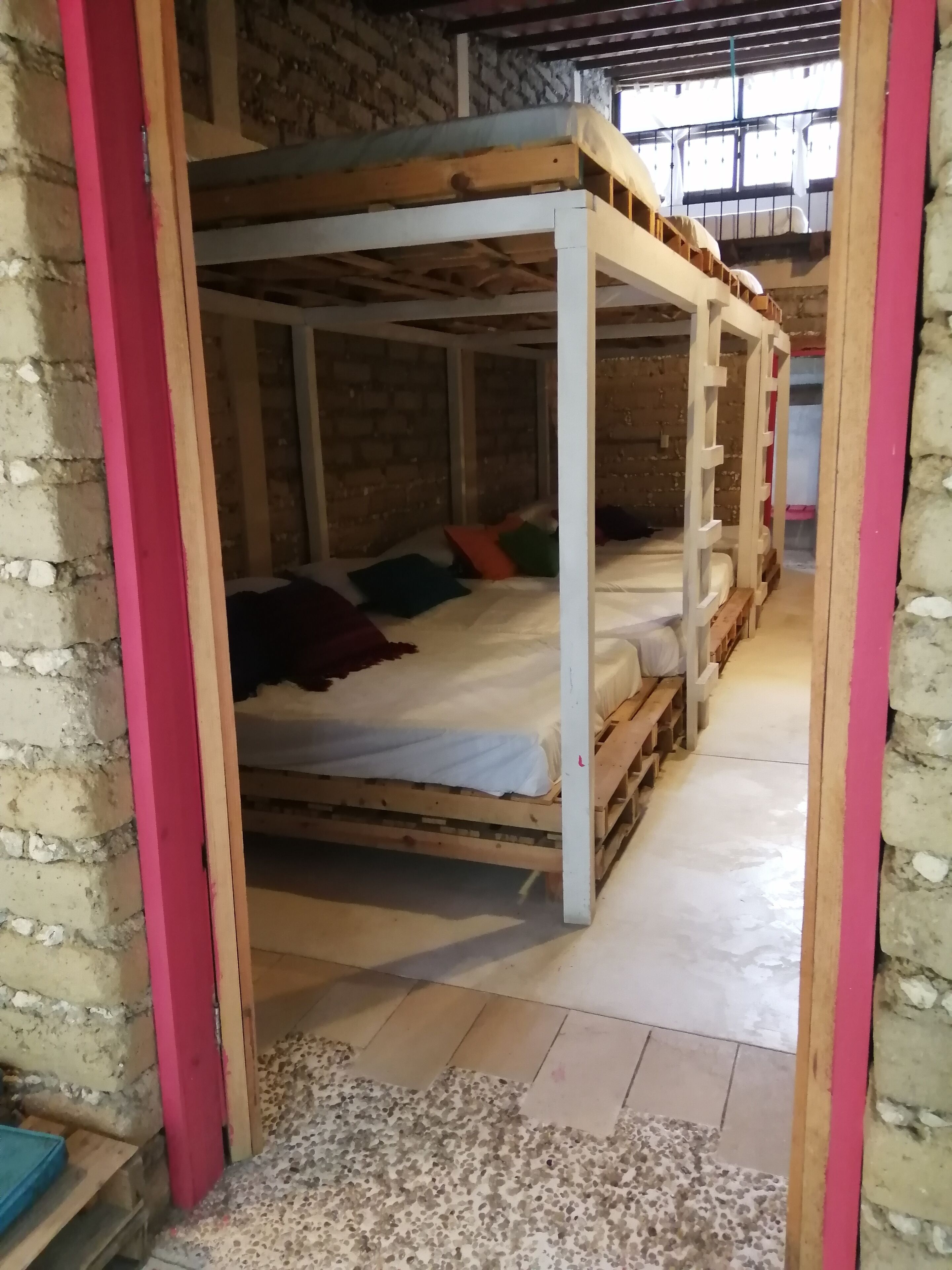 A rustic room with wooden bunk beds, a brick wall, and a concrete floor.