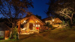 A stone building with a thatched roof, surrounded by trees and a grassy area. - Canto del Agua Ecolodge (Tzimol)
