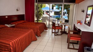 A hotel room with two beds, a desk with a chair, a laptop, and a view of the outside. - Hotel York (Guamuchil)
