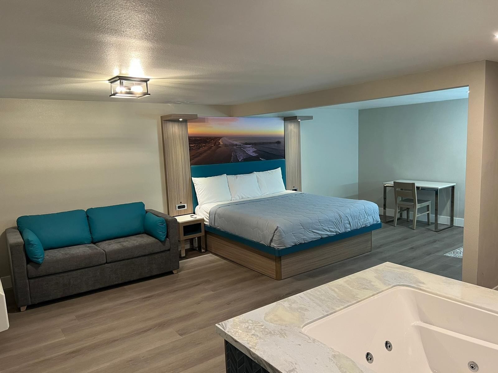 A hotel room with a bed, a sofa, a desk, and a bathtub.