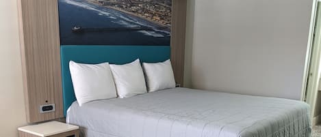 A modern bedroom with a large bed, a nightstand, and a cityscape mural on the wall.