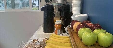 A breakfast buffet with bananas, apples, and packaged snacks.