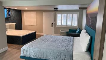 Un dormitorio moderno con una cama grande, un baño separado con tocador y vistas a la ciudad a través de las ventanas.