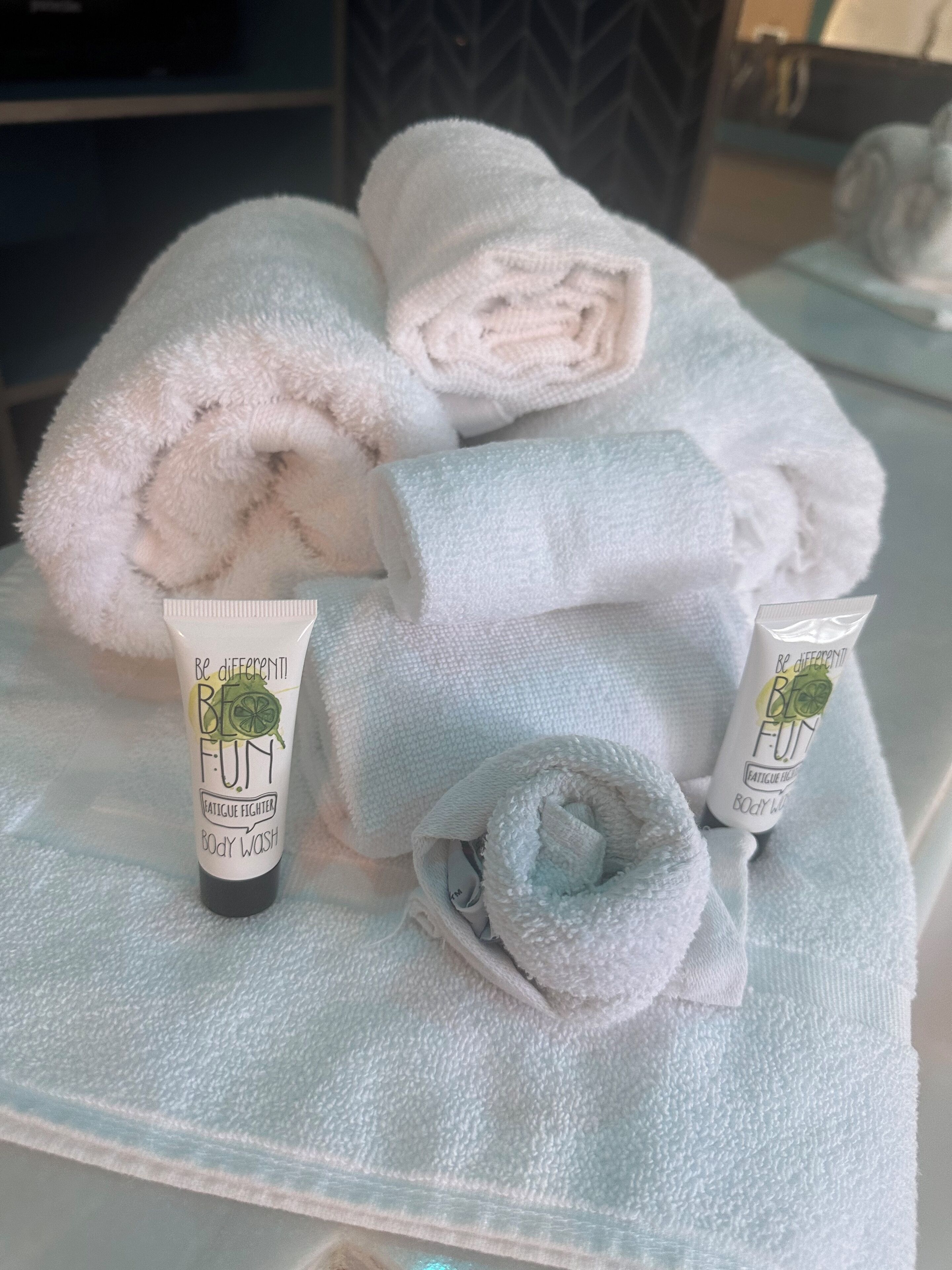 A bathroom with towels and two bottles of body wash.