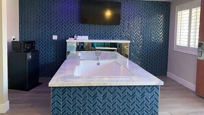 A modern kitchen with a central island, a built-in microwave, and a large flat-screen TV mounted on the wall. - Super 8 by Wyndham Oceanside Downtown (Oceanside)