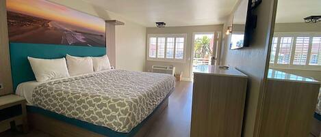 A bedroom with a bed, a desk, and a large window.