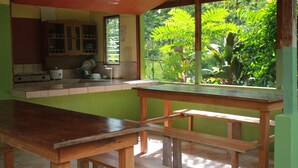 Una cocina con una mesa y banco de madera, una ventana con vistas a la vegetación y un letrero sobre la ventana.