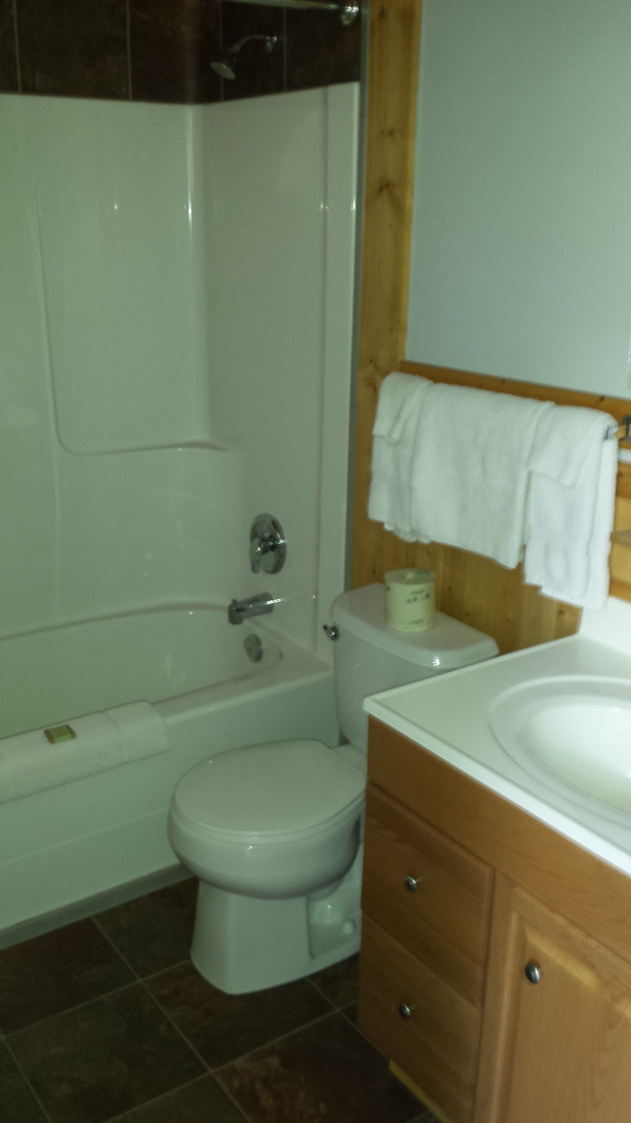 Een badkamer met bad, toilet en een houten wastafelmeubel.