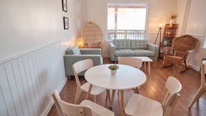 Una habitación acogedora con una mesa redonda blanca, varias sillas, un sofá y sillones de mimbre.