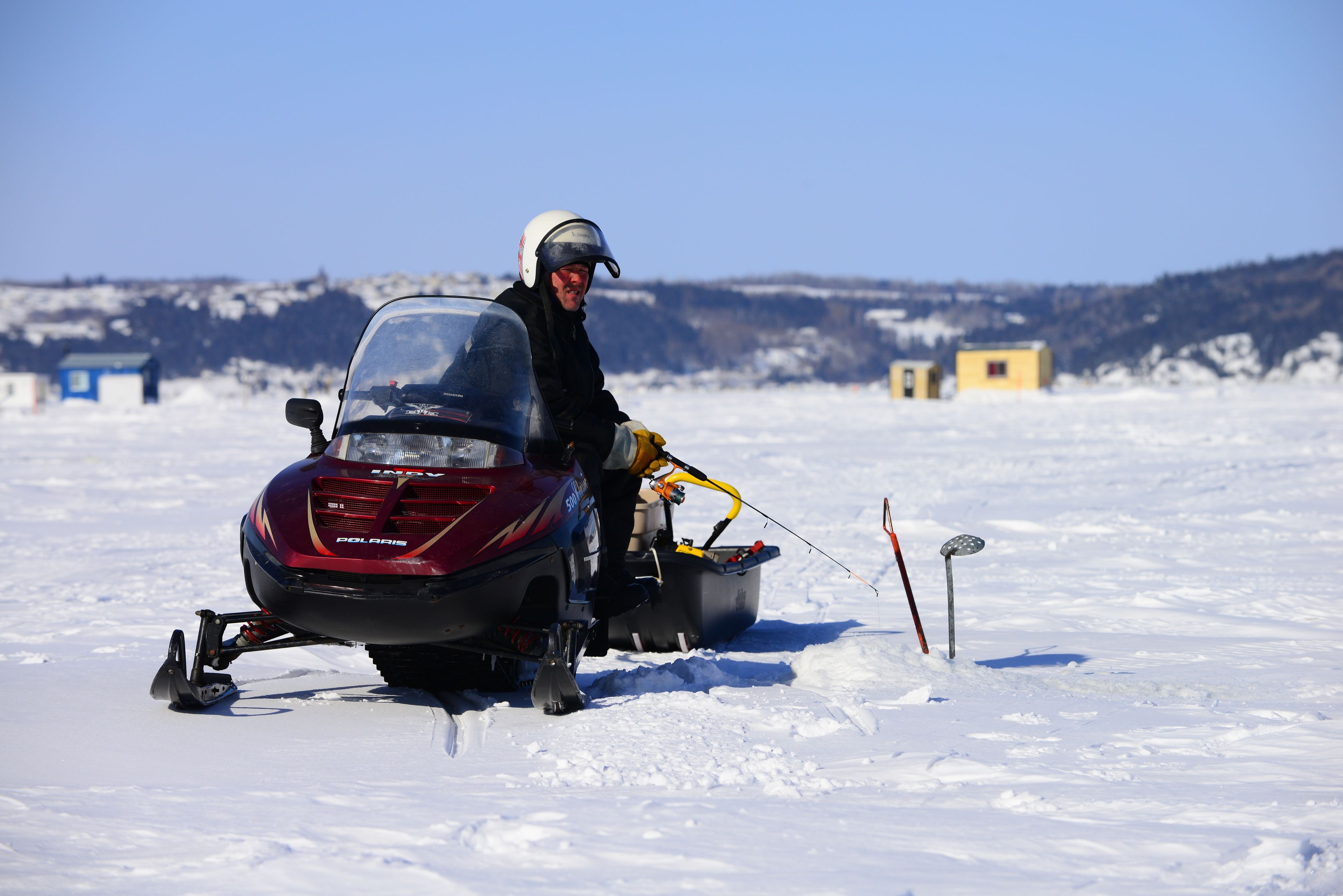 Une motoneige avec un conducteur portant des vêtements d’hiver et un casque.