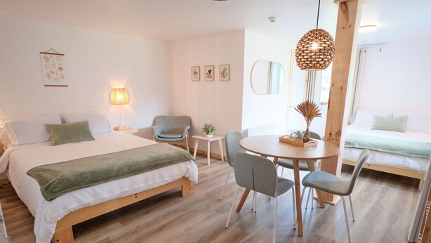 Un dormitorio moderno con una cama de madera, una mesa redonda y una silla.