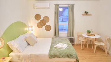 A bedroom with a bed, bedside table, and a small dining area with a table and chairs.