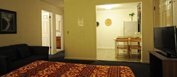 Habitación de hotel con cama, televisión, escritorio y sillas, y puerta que da a un baño.