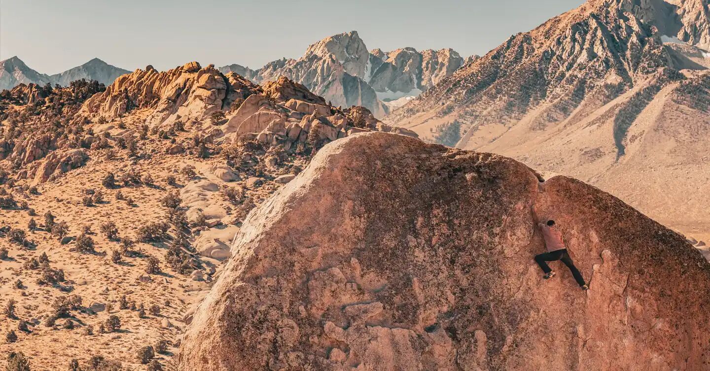 A rocky terrain with a person climbing a large rock.