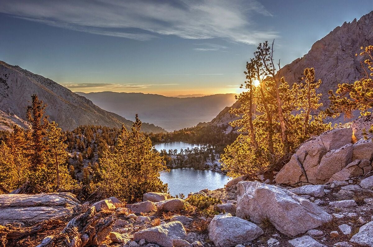 Un paysage montagneux avec un lac, des arbres et un terrain rocheux.