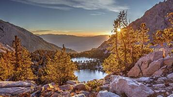A mountainous landscape with a lake, trees, and rocky terrain.