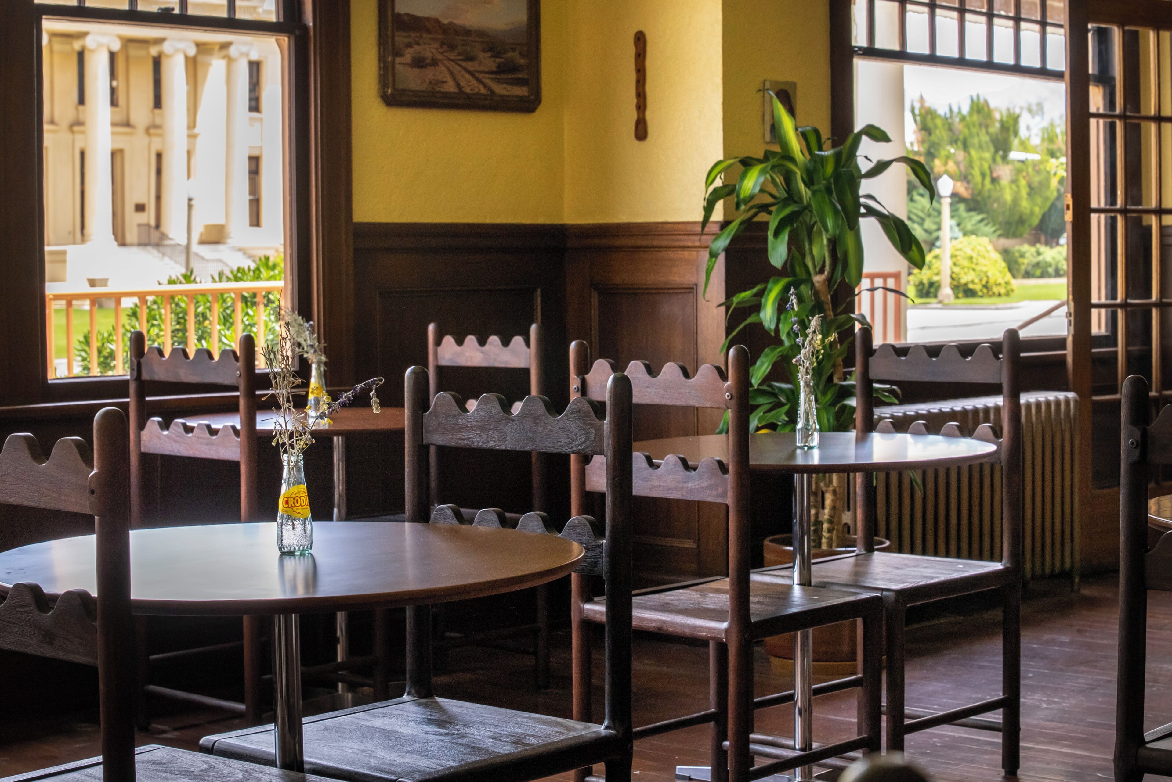 A restaurant interior with wooden furniture, a round table, and a view of a building outside.