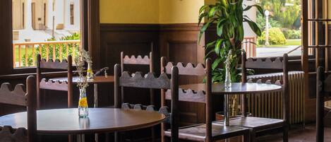 A restaurant interior with wooden furniture, a round table, and a view of a building outside.