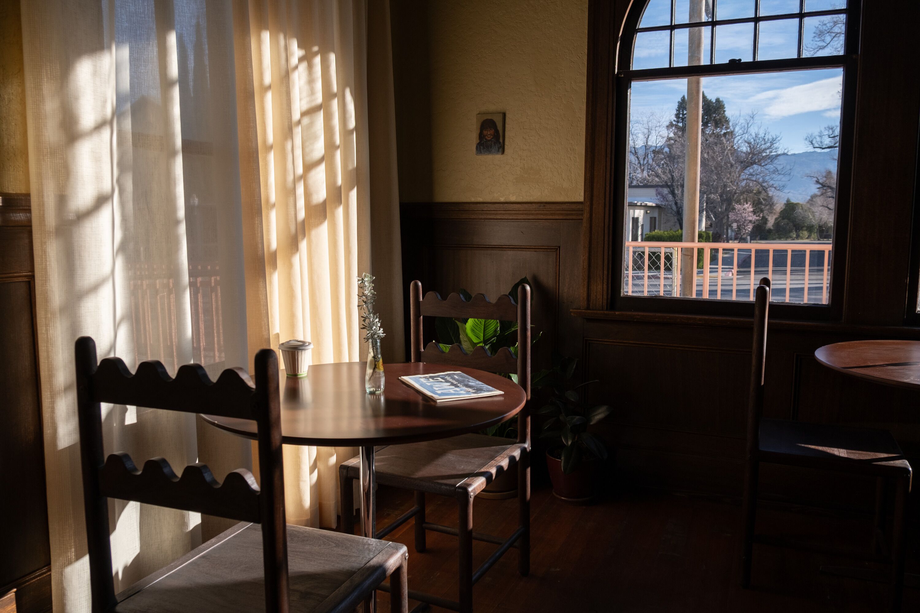 A room with a table, chairs, a window with a view, and a door.
