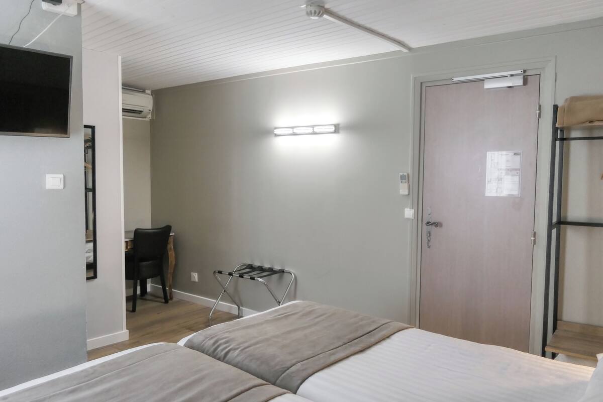 A bedroom with a bed, a desk, a chair, a wardrobe, and a door.