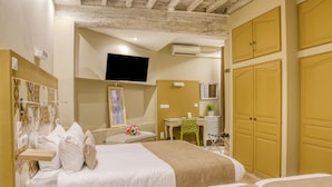 Une chambre d’hôtel avec deux lits, un bureau, une chaise, une télévision et une armoire.