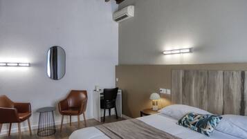 Habitación de hotel con cama, escritorio con silla, una mesa redonda y aire acondicionado instalado en la pared.
