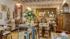 Un restaurant chaleureux avec des tables et des chaises en bois, un grand arrangement floral en guise de décoration centrale et un plafond rustique.