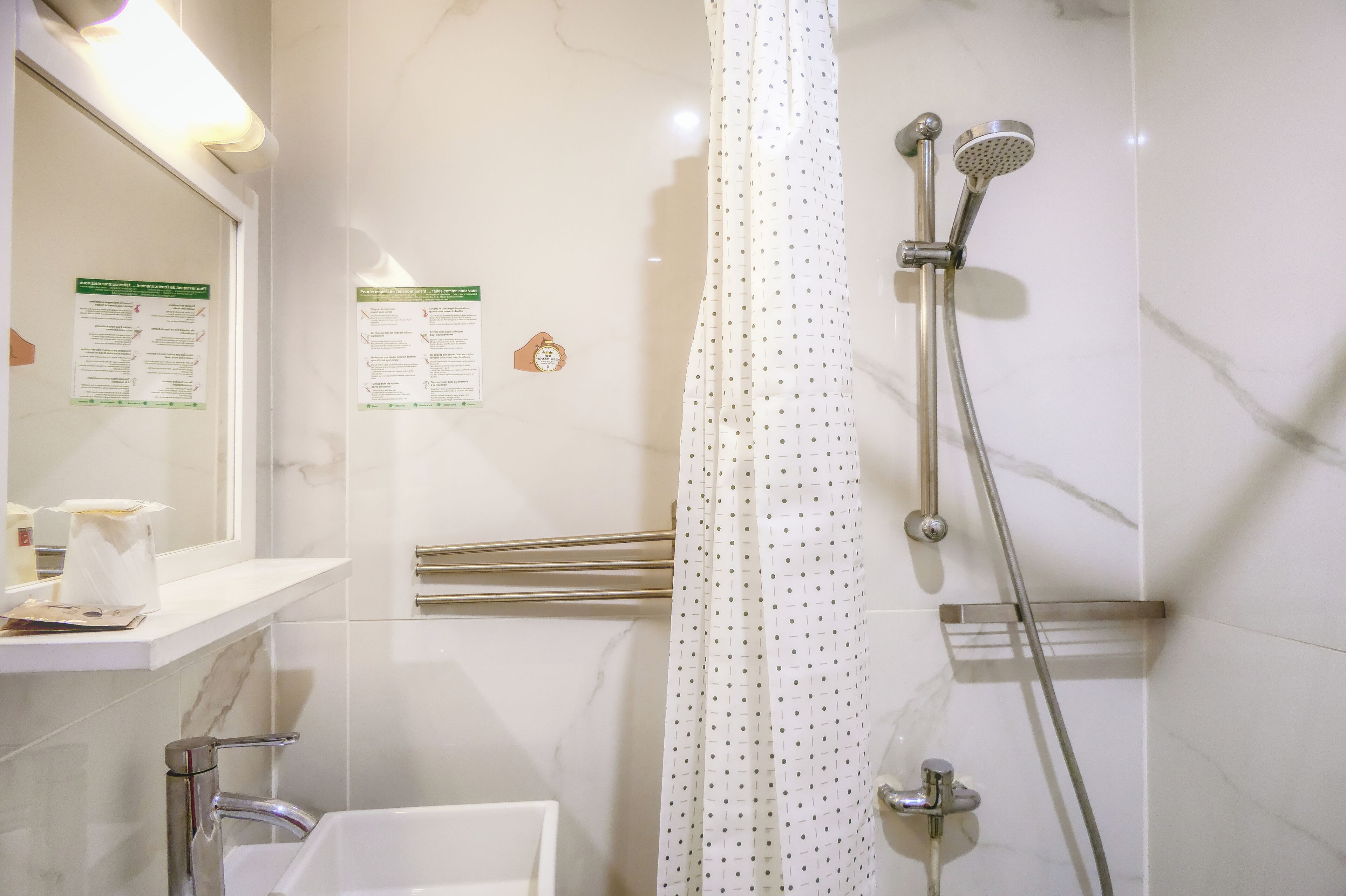 A bathroom with a shower, a sink, a mirror, and a towel rack.