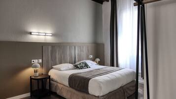 Une chambre à coucher comprenant un lit, des tables de chevet, une tête de lit et une fenêtre avec des rideaux.