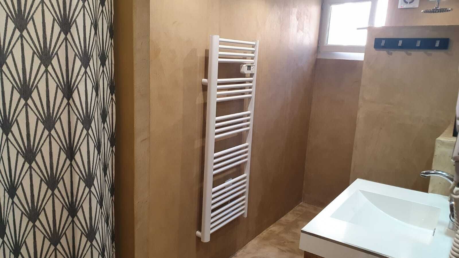Ein Badezimmer mit einem weißen Waschbecken, einem Handtuchhalter und einer Wand mit Muster.