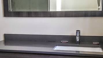 A bathroom with a dark wooden vanity, a sink, and a mirror. There are towels stacked under the vanity.