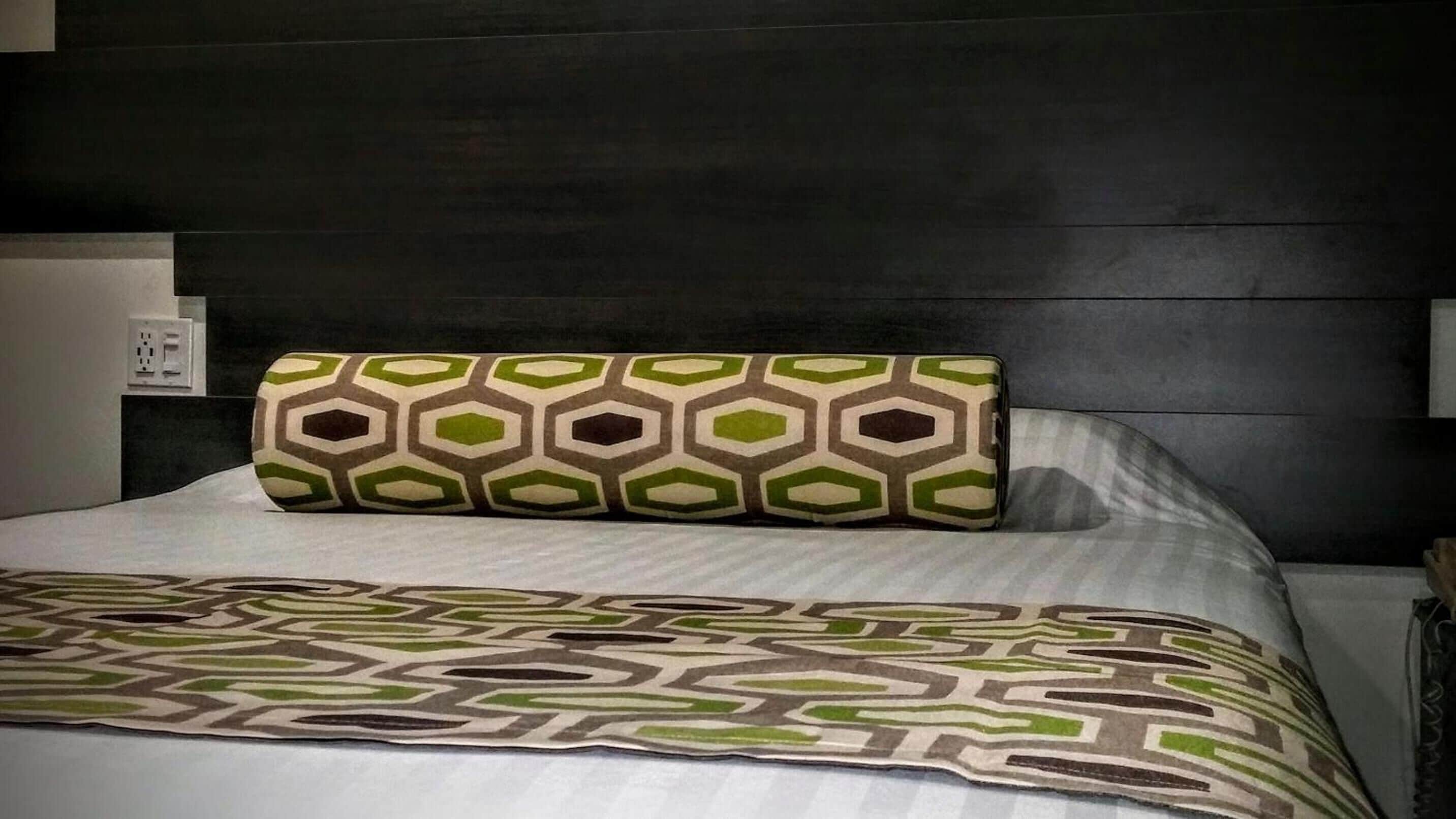 A bed with a patterned pillow and a geometric throw blanket.