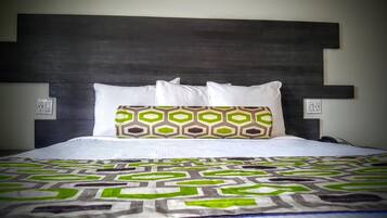 A bed with a patterned bedspread, a headboard with a geometric design, and two bedside lamps.