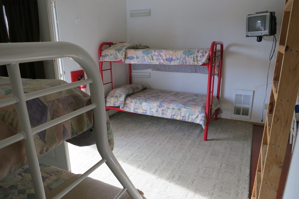 A bunk bed room with a television mounted on the wall.