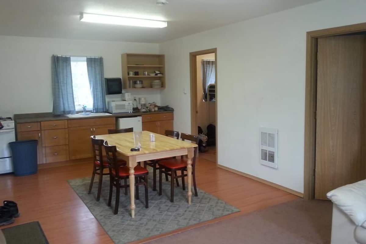 A compact living space with a dining area, kitchenette, and a door leading to another room.
