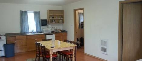A compact living space with a dining area, kitchenette, and a door leading to another room.