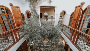 A multi-level interior with wooden balconies, a central tree, and a hanging light fixture. - Dar Nour El Houda (Marrakech)