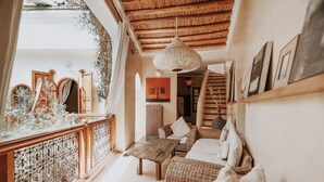 A cozy interior with a wooden ceiling, a wicker sofa, a dining table, and a staircase. - Dar Nour El Houda (Marrakech)