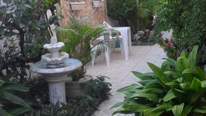 A garden area with a fountain, potted plants, and a white table and chair set. - Pousada Montreux (Mata de São João)